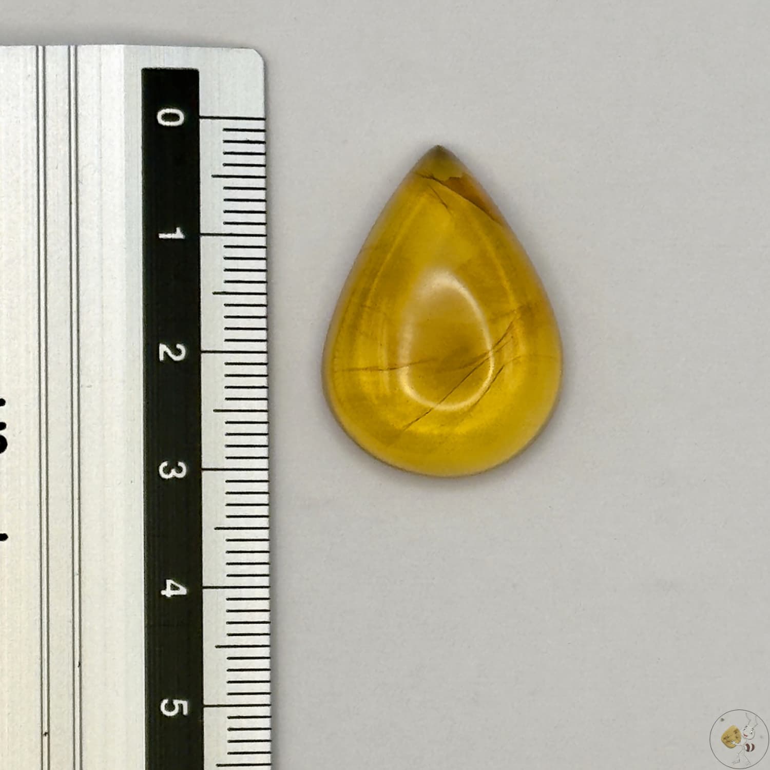 Cabochon en ambre jaune du Mexique, forme goutte, avec des inclusions naturelles et une finition polie. Présenté avec une règle pour référence