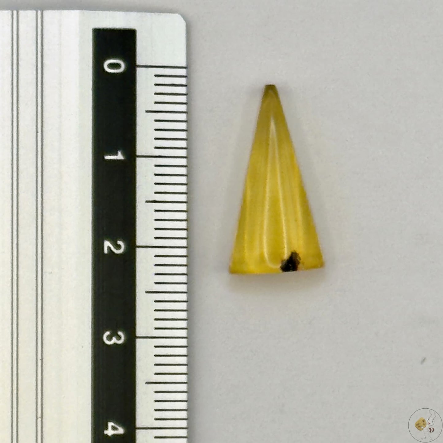 Cabochon en ambre jaune du Mexique, forme triangulaire, avec des inclusions naturelles et une finition polie. Présenté avec une règle pour référence